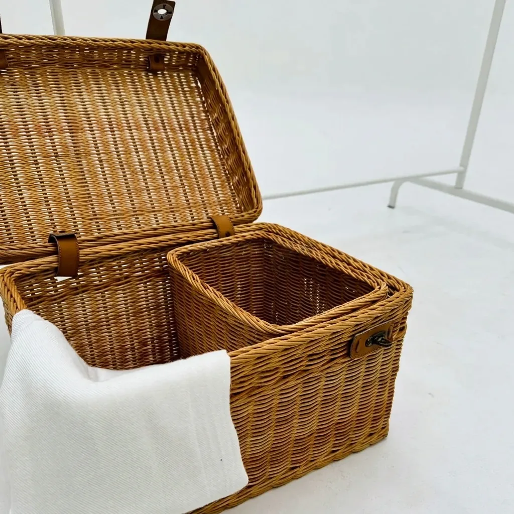 Natural honey rattan hamper basket with a fabric-lined interior, leather straps and metal clasp